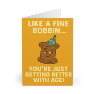 Funny sewing birthday card with cartoon bobbin wearing a party hat and text “Like a fine bobbin… you’re just getting better with age!” — perfect for sewing lovers | by T Larkin.